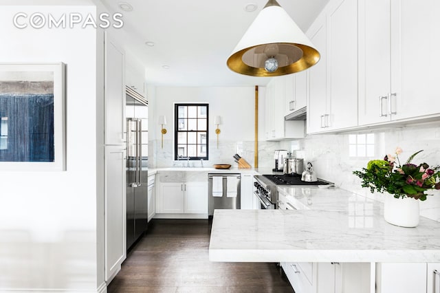975 Park Ave Unit 14D, New York City, NY 10028 - kitchen featuring appliances with stainless steel finishes, a peninsula, white cabinetry, and light stone countertops