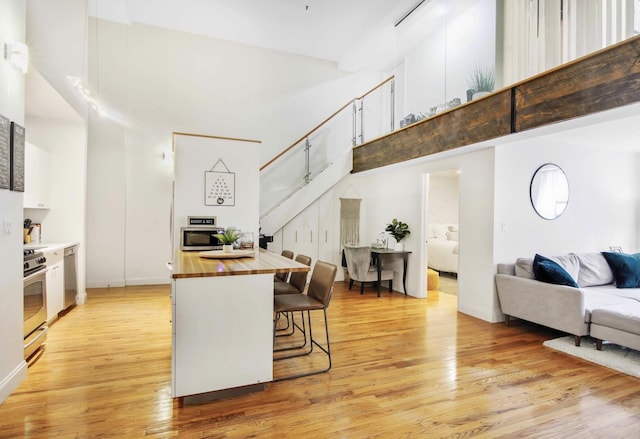 259 21st St Unit 1C, New York City, NY 11215 - kitchen featuring butcher block counters, a towering ceiling, light wood-type flooring, appliances with stainless steel finishes, and open floor plan