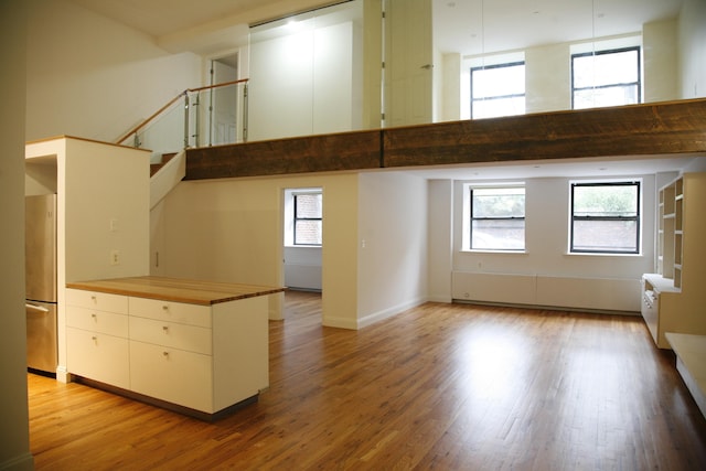 259 21st St Unit 1C, New York City, NY 11215 - spare room featuring a towering ceiling, light wood-style floors, and stairs