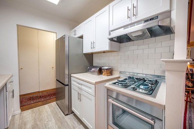 315 W 232nd St Unit 3-C, New York City, NY 10463 - kitchen with under cabinet range hood, stainless steel appliances, light countertops, backsplash, and white cabinets