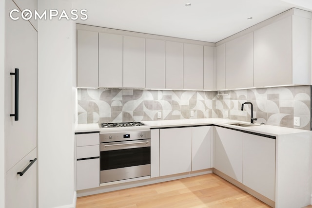 176 W 87th St Unit 1H, New York City, NY 10024 - kitchen with oven, a sink, white cabinets, light countertops, and modern cabinets