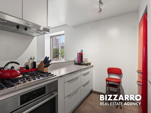 300 W 135th St Unit 8A, New York City, NY 10030 - kitchen featuring oven, range hood, dark tile patterned floors, light countertops, and modern cabinets