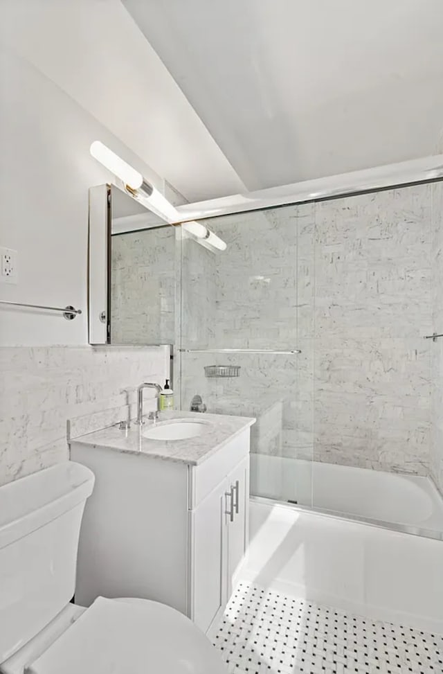 233 E 69th St Unit 11-B, New York City, NY 10021 - full bathroom with vanity, toilet, bath / shower combo with glass door, tile walls, and tile patterned flooring