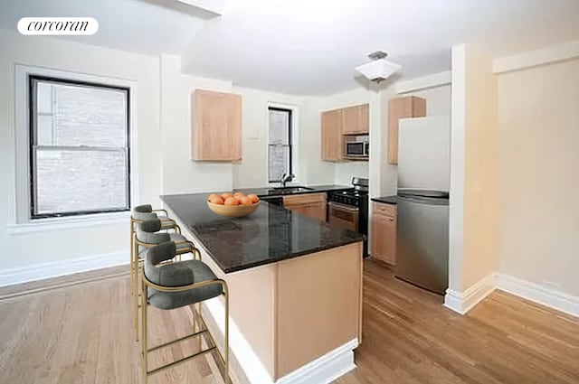 40 W 72nd St Unit 106, New York City, NY 10023 - kitchen featuring appliances with stainless steel finishes, dark countertops, light wood-style flooring, baseboards, and light brown cabinetry