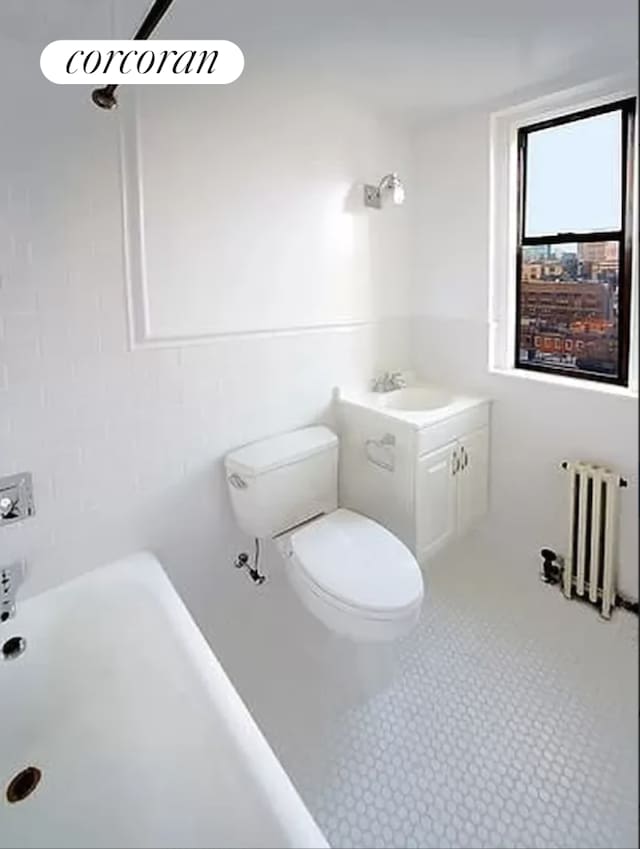 40 W 72nd St Unit 106, New York City, NY 10023 - bathroom with radiator heating unit, vanity, a bathtub, and toilet