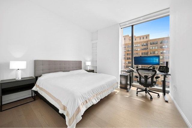 277 5th Ave Unit 25D, New York City, NY 10016 - bedroom with wood-type flooring, floor to ceiling windows, a desk, and baseboards