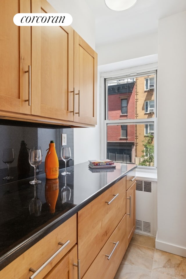 150 E 77th St Unit 3D, New York City, NY 10075 - kitchen featuring radiator heating unit, light brown cabinets, dark countertops, baseboards, and light tile patterned flooring