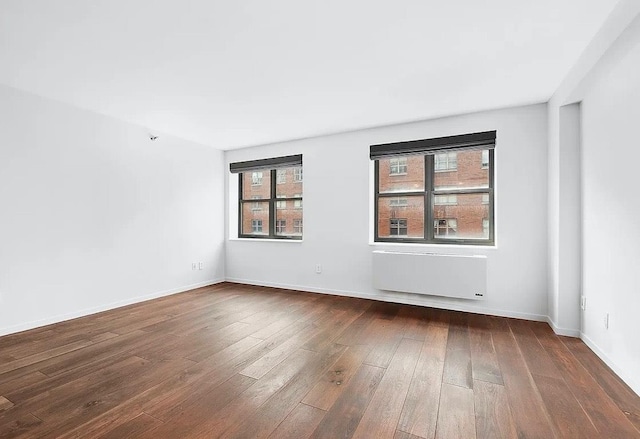 516 W 47th St Unit N-4D, New York City, NY 10036 - empty room featuring radiator, plenty of natural light, dark wood-type flooring, and baseboards