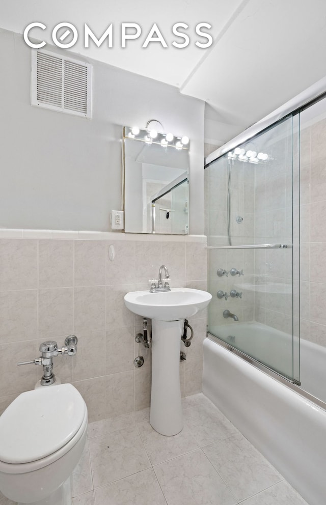 102 W 85th St Unit 9B, New York City, NY 10024 - full bath featuring bath / shower combo with glass door, tile walls, tile patterned flooring, and toilet