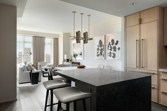 543 W 122nd St Unit 11A, New York City, NY 10027 - kitchen with a chandelier, dark wood finished floors, a kitchen bar, and a kitchen island