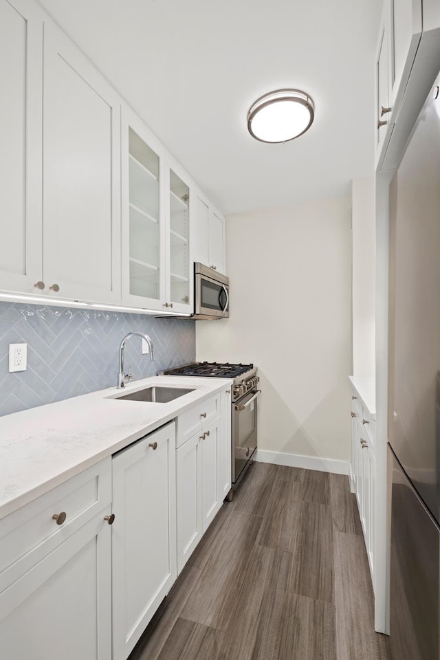 345 E 81st St Unit 11D, New York City, NY 10028 - kitchen with stainless steel appliances, a sink, dark wood finished floors, decorative backsplash, and glass insert cabinets