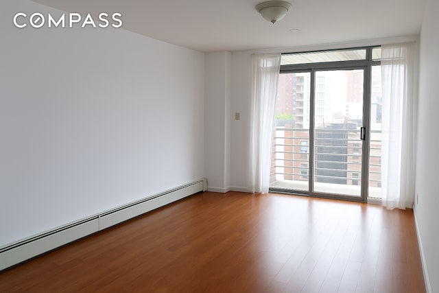 31 Monroe St Unit 9B, New York City, NY 10002 - unfurnished room featuring a baseboard heating unit and wood finished floors