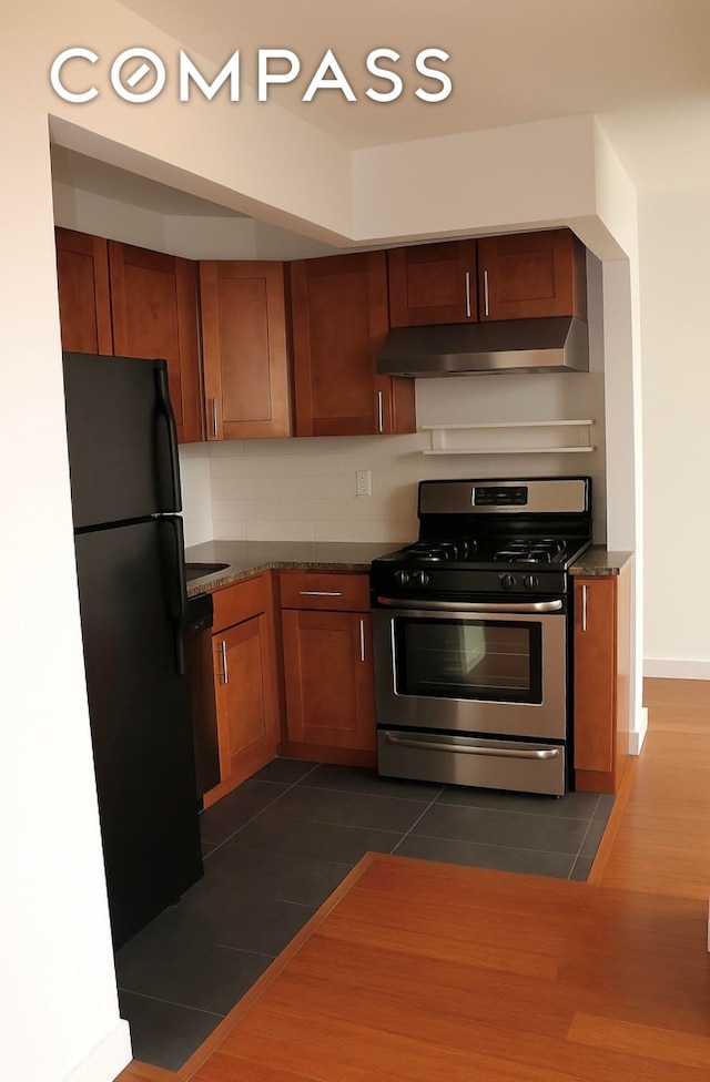 31 Monroe St Unit 9B, New York City, NY 10002 - kitchen featuring stainless steel appliances, under cabinet range hood, brown cabinetry, and decorative backsplash