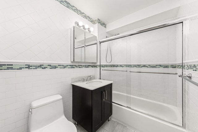 30-63 38th St Unit 2C, New York City, NY 11103 - bathroom featuring vanity, combined bath / shower with glass door, tile walls, toilet, and tile patterned floors