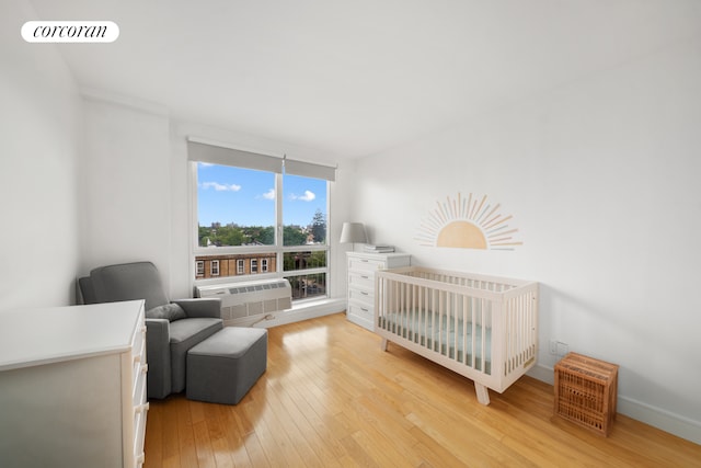103 Quentin Rd Unit B503, New York City, NY 11223 - bedroom featuring light wood finished floors, a wall mounted AC, a nursery area, and baseboards