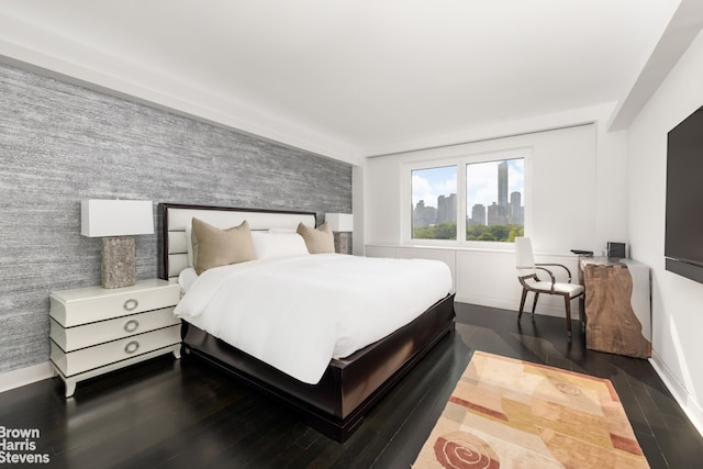 860 5th Ave Unit 11H, New York City, NY 10065 - bedroom with baseboards, dark wood-style floors, and an accent wall
