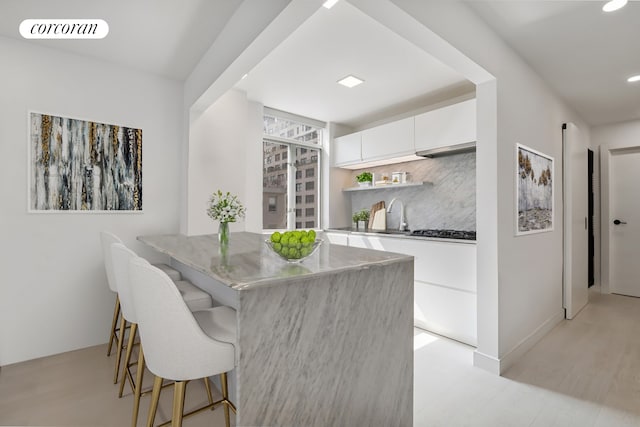 200 E 58th St Unit 12A, New York City, NY 10022 - kitchen with white cabinetry, a kitchen bar, modern cabinets, a sink, and open shelves