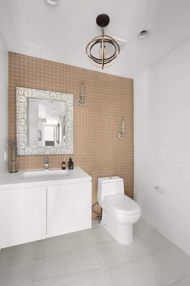 216 E 47th St Unit 12A, New York City, NY 10017 - bathroom featuring tile walls, toilet, vanity, and tile patterned flooring