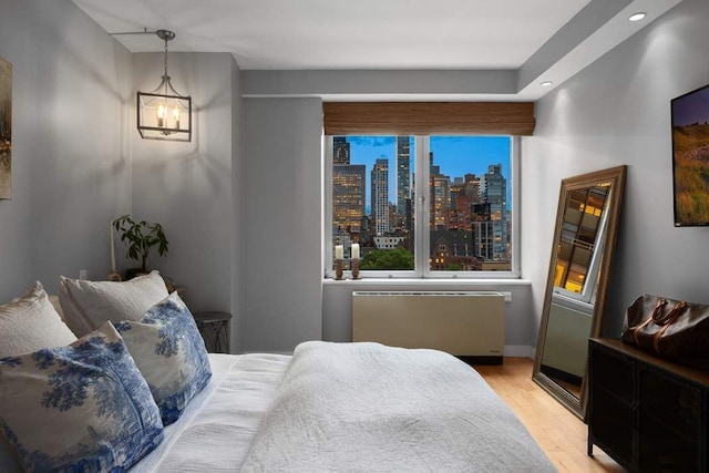 216 E 47th St Unit 12A, New York City, NY 10017 - bedroom featuring light wood-type flooring, radiator, recessed lighting, a chandelier, and baseboards