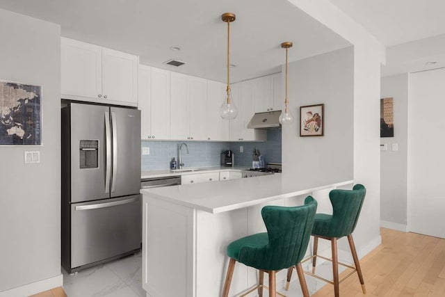 216 E 47th St Unit 12A, New York City, NY 10017 - kitchen featuring appliances with stainless steel finishes, under cabinet range hood, white cabinets, and light countertops