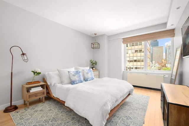 216 E 47th St Unit 12A, New York City, NY 10017 - bedroom with radiator, light wood-type flooring, and baseboards
