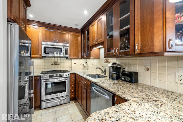 235 E 57th St Unit 14C, New York City, NY 10022 - kitchen featuring appliances with stainless steel finishes, a sink, light stone countertops, light tile patterned flooring, and decorative backsplash