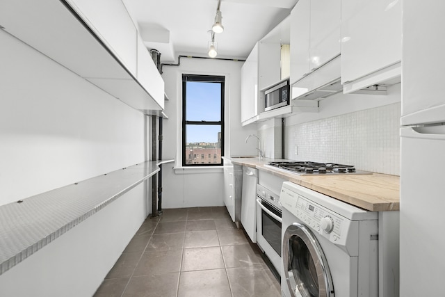 675 W End Ave Unit 11C, New York City, NY 10025 - kitchen with washer / dryer, stainless steel appliances, white cabinetry, a sink, and decorative backsplash