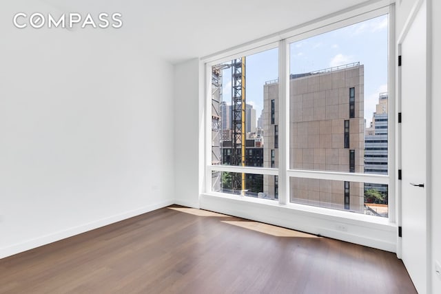 111 Murray St Unit 11C, New York City, NY 10007 - empty room with wood finished floors, a skyline view, and baseboards