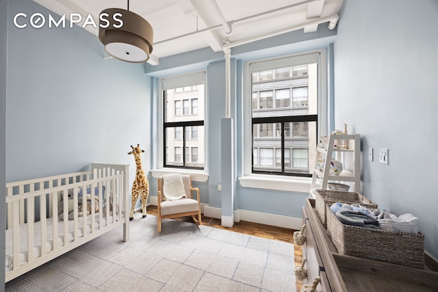129 W 22nd St Unit 5A, New York City, NY 10011 - bedroom with beam ceiling, a nursery area, wood finished floors, and baseboards