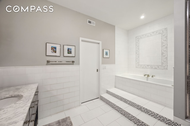 129 W 22nd St Unit 5A, New York City, NY 10011 - bathroom with tile walls, tile patterned flooring, vanity, a garden tub, and wainscoting