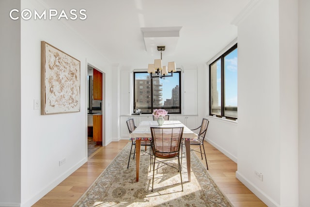 171 E 84th St Unit 31C, New York City, NY 10028 - dining area with a chandelier, light wood-type flooring, and baseboards