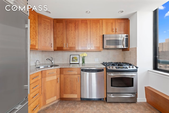 171 E 84th St Unit 31C, New York City, NY 10028 - kitchen with stainless steel appliances, a sink, backsplash, light stone countertops, and brown cabinetry