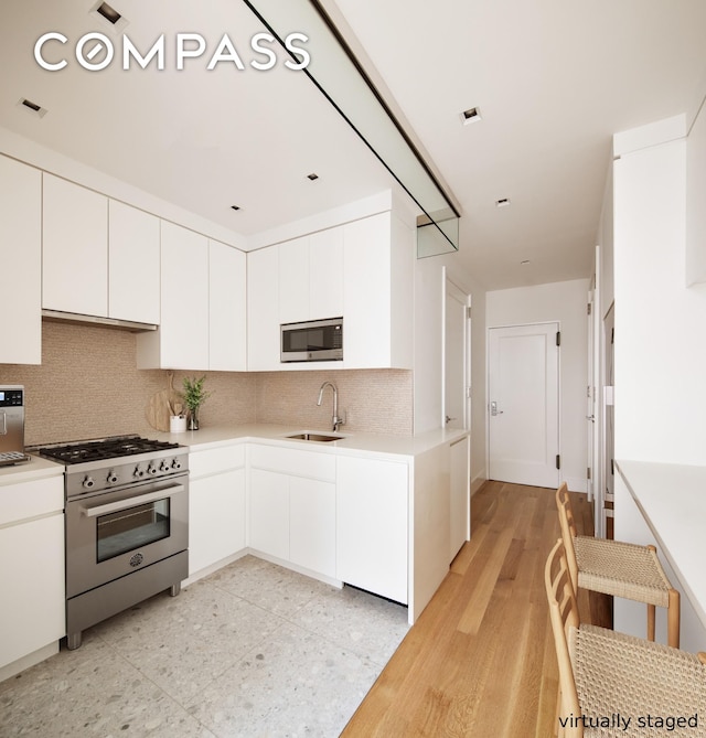 435 E 85th St Unit 4F, New York City, NY 10028 - kitchen with appliances with stainless steel finishes, a sink, tasteful backsplash, light countertops, and white cabinetry