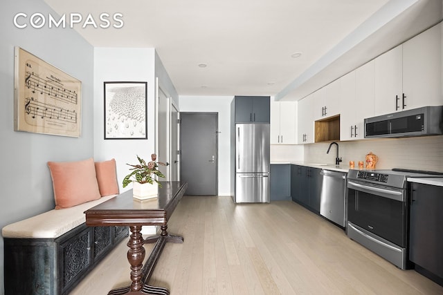 511 Evergreen Ave Unit 3D, New York City, NY 11221 - kitchen with stainless steel appliances, light countertops, backsplash, a sink, and light wood-style floors