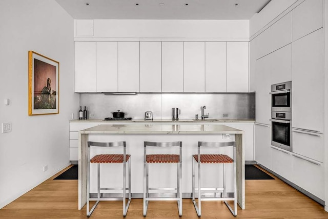 30 E 21st St Unit 3B, New York City, NY 10010 - kitchen with a kitchen bar, light countertops, white cabinets, and a sink