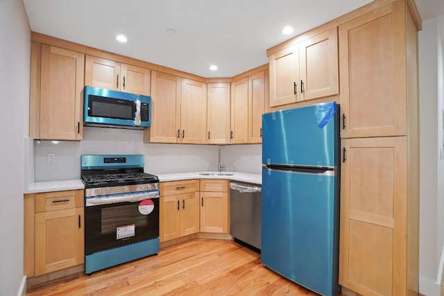 60-14 Menahan St, New York City, NY 11385 - kitchen with appliances with stainless steel finishes, light brown cabinetry, light wood-style flooring, light countertops, and recessed lighting