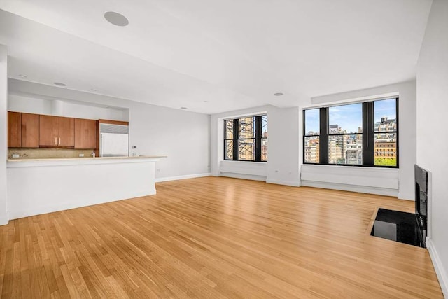 124 Hudson St Unit 6D, New York City, NY 10013 - unfurnished living room featuring light wood finished floors, baseboards, and a fireplace with flush hearth