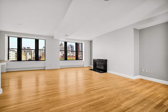 124 Hudson St Unit 6D, New York City, NY 10013 - unfurnished living room featuring light wood-type flooring, a tiled fireplace, and baseboards