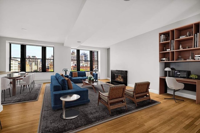 124 Hudson St Unit 6D, New York City, NY 10013 - living room featuring light wood-type flooring, a fireplace with flush hearth, an office area, and baseboards
