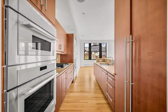 124 Hudson St Unit 6D, New York City, NY 10013 - kitchen with light wood-style floors, a sink, double oven, and stainless steel gas stovetop