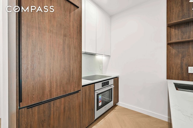 90 Herbert St Unit 3A, New York City, NY 11222 - kitchen with oven, black electric stovetop, white cabinetry, light countertops, and baseboards