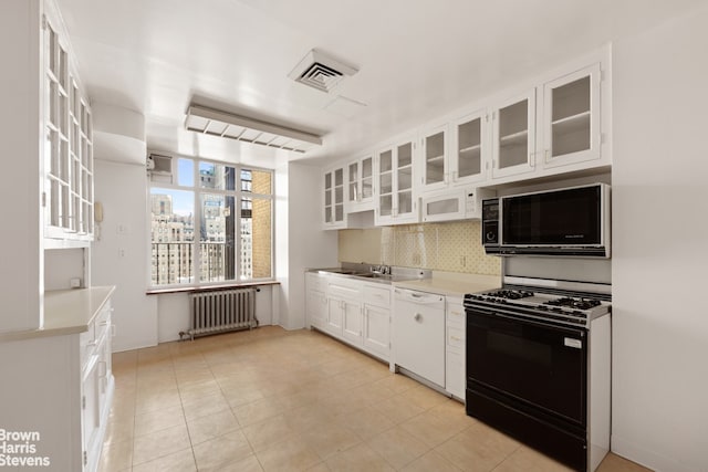 956 5th Ave Unit 11Thfloor, New York City, NY 10075 - kitchen featuring radiator heating unit, white dishwasher, black gas stove, decorative backsplash, and white cabinets