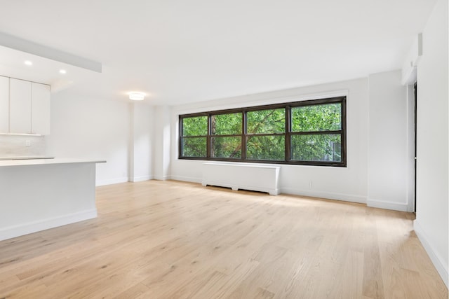 142 W End Ave Unit 2U, New York City, NY 10023 - unfurnished living room with radiator, light wood-style flooring, and recessed lighting