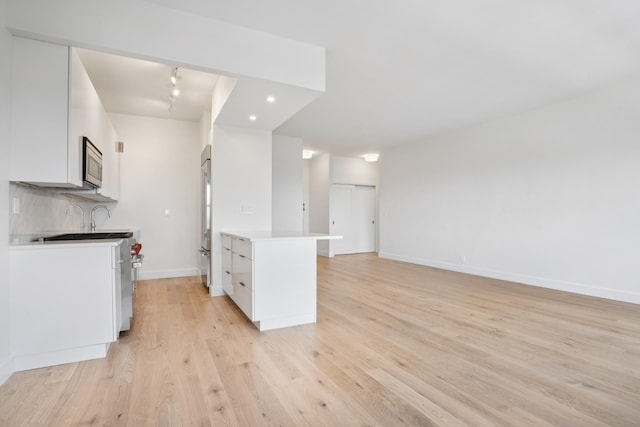 180 W End Ave Unit 30R, New York City, NY 10023 - kitchen with appliances with stainless steel finishes, white cabinetry, light wood-style flooring, light countertops, and a peninsula