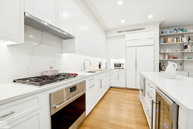 780 W End Ave Unit M1, New York City, NY 10025 - kitchen featuring built in appliances, beverage cooler, ventilation hood, white cabinets, and recessed lighting