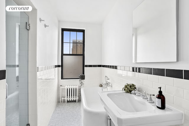 170 2nd Ave Unit 9B, New York City, NY 10003 - bathroom featuring radiator, tile walls, a shower stall, a freestanding bath, and a wainscoted wall