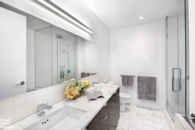 99 Warren St Unit 11C, New York City, NY 10007 - bathroom featuring marble look tiles, double vanity, a stall shower, toilet, and tile walls