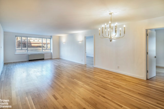 30 E 62nd St Unit 11A, New York City, NY 10065 - unfurnished room featuring radiator heating unit, a chandelier, light wood-style floors, and baseboards