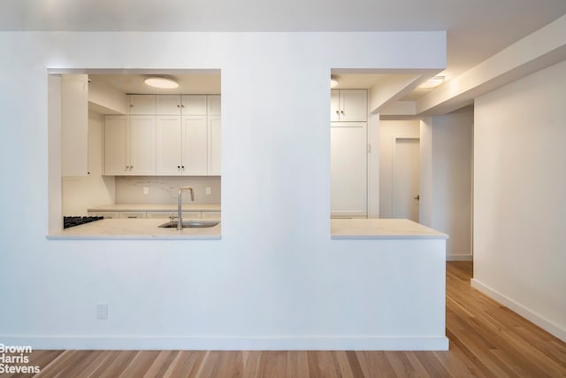 30 E 62nd St Unit 11A, New York City, NY 10065 - kitchen featuring a sink, baseboards, white cabinets, and wood finished floors