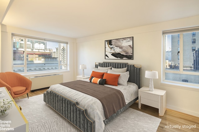 30 E 62nd St Unit 11A, New York City, NY 10065 - bedroom featuring radiator heating unit, wood finished floors, and baseboards